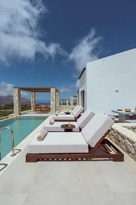 three beds sitting on a balcony next to a swimming pool at Ethereal White Villas in Gramvousá