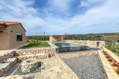 a backyard with a swimming pool and a stone wall at Villa Alargo Heated Pool in Katokhórion