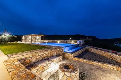 a backyard with a swimming pool and a stone wall at Villa Alargo Heated Pool in Katokhórion