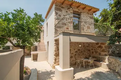 a building with a balcony and a table on a patio at Το Ρόδι Voutas Cottage house in Palaiochóra