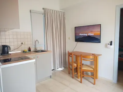 a kitchen with a table and a tv on the wall at Elysian Garden in Kalyves