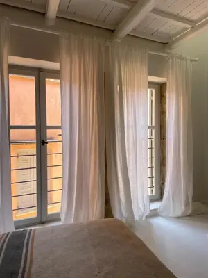 a bedroom with white curtains and a large window at Reas House in Chania Town