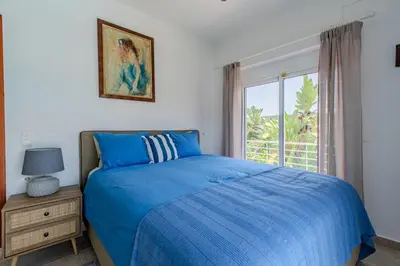 a bedroom with a blue bed and a window at Villa Xamadochori in Xamoudhokhórion
