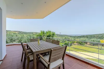 a wooden table and chairs on a balcony at Villa Xamadochori in Xamoudhokhórion