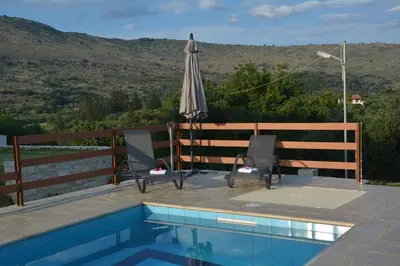 an umbrella and chairs next to a swimming pool at Villa Ikaros in Kalamitsi Amygdali