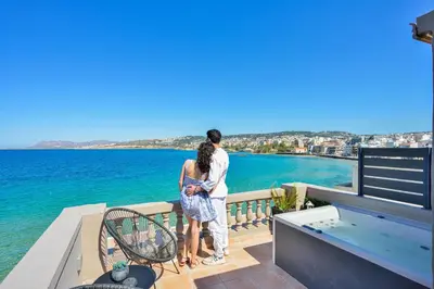 a man and woman standing on a balcony looking at the water at Kumka seafront suite in Chania Town