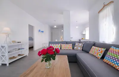 a living room with a blue couch and a vase with red roses at Kallimento in Kissamos