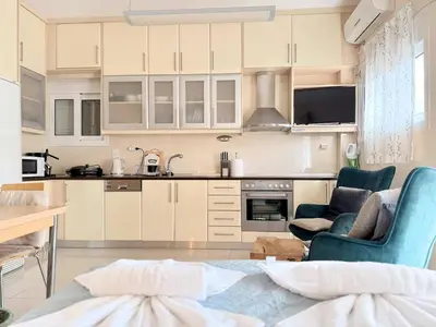 a kitchen with white cabinets and blue chairs at Little Central Apartment-1min walk from everywhere in Chania Town