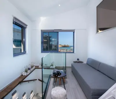 a living room with a couch and two windows at Blue Balcony - Boutique Beachfront Suite with Private Parking Spot in Chania Town