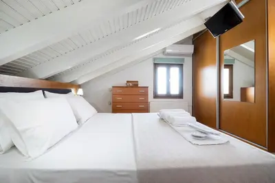 a bedroom with a large white bed with a mirror at Loft Apartment in Chania Town