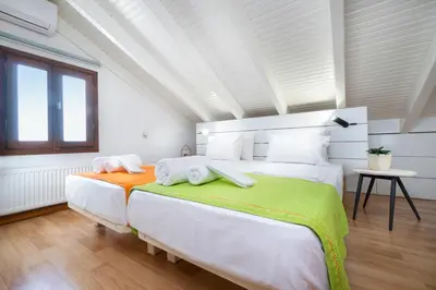 a white bedroom with two beds and a window at Loft Apartment in Chania Town