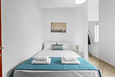 a white bedroom with a large bed with two pillows at Marika's Apartment in Chania in Chania Town