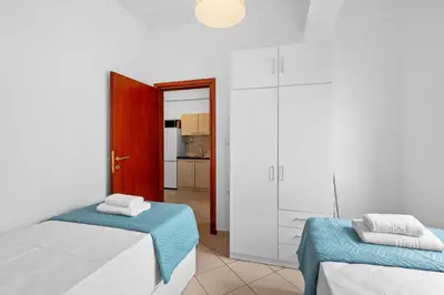 a white room with two beds and a kitchen at Marika's Apartment in Chania in Chania Town