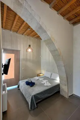 a bedroom with a large bed with a stone wall at Evans Villas in Kissamos