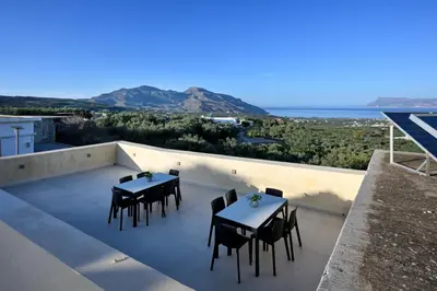 a patio with tables and chairs on the roof of a house at Evans Villas in Kissamos