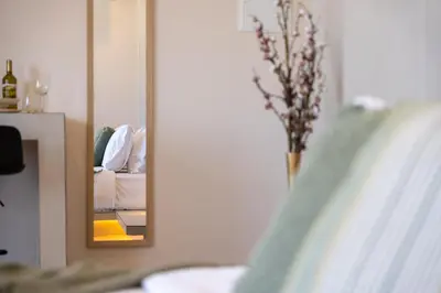 a mirror in a bedroom with a bed and a vase of flowers at Selected Suites in Chania Town