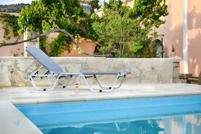 a chair sitting next to a swimming pool at Villa Rouga by Andrian Villas in Kalamítsion Alexándrou