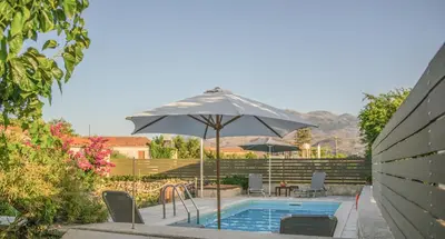 a pool with an umbrella and chairs and a table at Villa Rouga by Andrian Villas in Kalamítsion Alexándrou