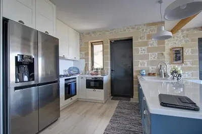 a kitchen with a stainless steel refrigerator and white cabinets at Villa Simera, with pool & great view in Fournádhos
