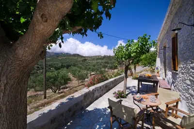 a patio with a table and chairs and a tree at Kallimento-Dimitra in Kissamos