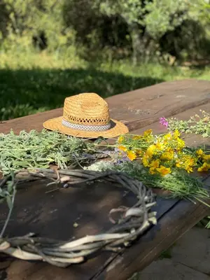 a straw hat sitting on a wooden table with flowers at WHITE MOUNTAINS Nature Home in Arménoi