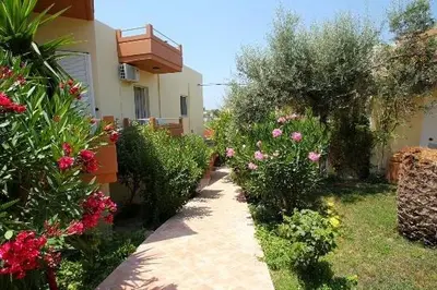a garden with flowers and a house with a walkway at Nea Kydonia suites and studios in Daratso