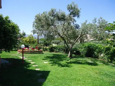 a garden with a tree and a bench in the grass at Nea Kydonia suites and studios in Daratso
