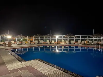 a large swimming pool with chairs and umbrellas at night at Nea Kydonia suites and studios in Daratso
