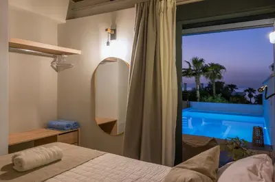 a bedroom with a bed and a window with a pool at Natura Hill Villa II Sunset View in Kounoupidhianá