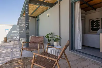 a patio with two chairs on a balcony at Natura Hill Villa II Sunset View in Kounoupidhianá