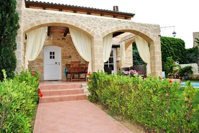 a stone house with an archway and a patio at Rock House's Villa Melody in Plataniás