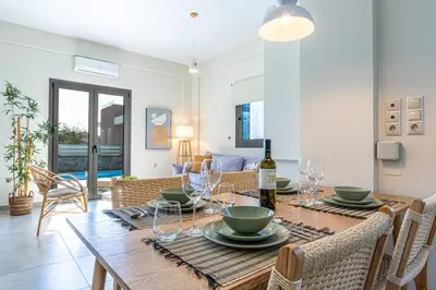 a dining room with a table with a bottle of wine at Anassa Natura Villa in Daratso