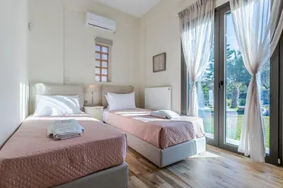 two beds in a bedroom with a large window at Anassa Natura Villa in Daratso