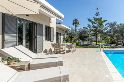 a patio with a table and chairs and a swimming pool at Anassa Natura Villa in Daratso