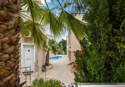 a palm tree next to a building with a pool at Relax Private Pool House in Maleme