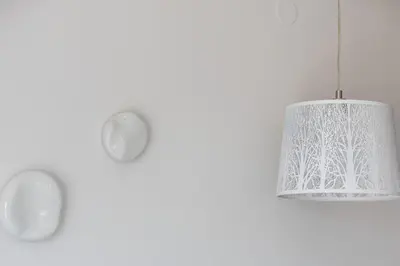 a white pendant light hanging from a white wall at Feli Living in Spiliá