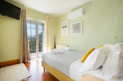 a bedroom with a bed with white sheets and a window at Casa BI LA in Galatás