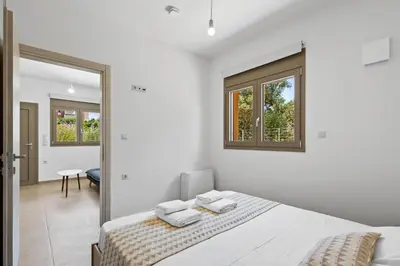 a white bedroom with a bed and a mirror at AURA - Deluxe Apartment in Chania Town