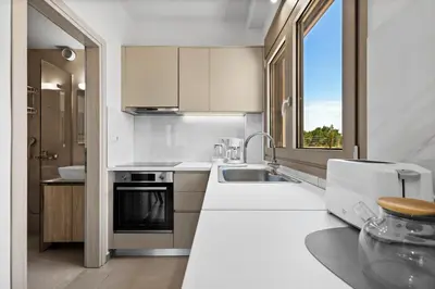 a kitchen with white counters and a sink and a window at AURA - Deluxe Apartment in Chania Town