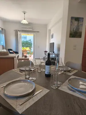 a table with plates and glasses and a bottle of wine at Van Gogh & Monet apartments in Maleme