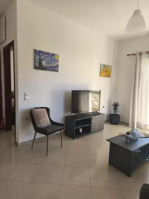 a living room with a tv and a chair at Van Gogh & Monet apartments in Maleme
