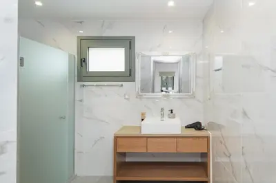 a white bathroom with a sink and a mirror at Villa Lakioto in Dhémbla
