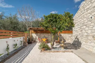 a patio with a tree and a stone wall at Villa Lakioto in Dhémbla