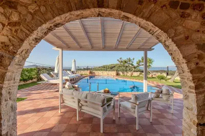 an archway over the patio of a villa with a swimming pool at Villa Trouli by Vintage Travel in Metókhi