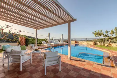 a patio with a table and chairs and a swimming pool at Villa Trouli by Vintage Travel in Metókhi