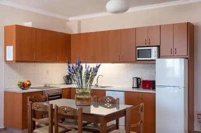 a kitchen with wooden cabinets and a table and a refrigerator at Villa Halepi by PosarelliVillas in Gavalochori