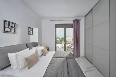 a white bedroom with a large bed and a balcony at Galanakis luxury villa in Chania Town