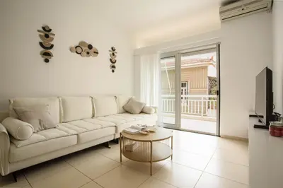 a living room with a white couch and a table at Be Crete - Miramare apartment in Chania Town