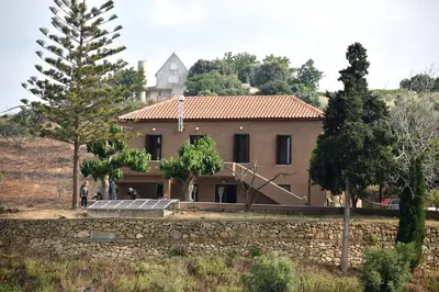 a large house with a stone wall and trees at Telesilla's home in Apothíkai