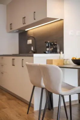 a kitchen with two white chairs in front of a counter at Theni City Apartment by Zen Estate in Chania Town